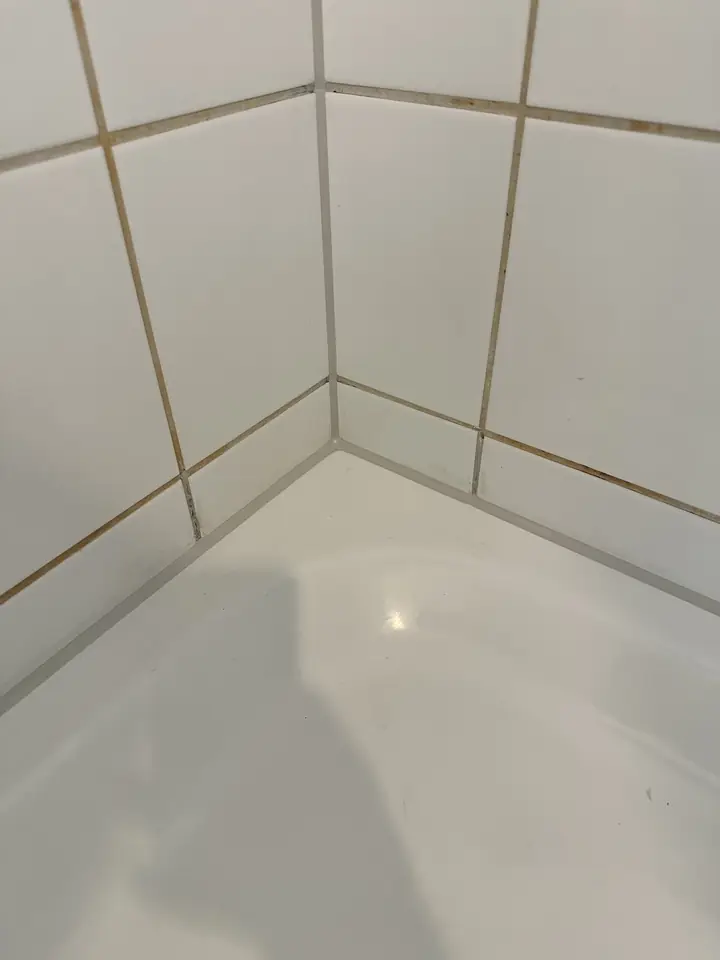 Dieselbe Wandecke über der Badewanne, in der Ecke und am Wannenrand verläuft jetzt eine schmale hellgraue Fuge