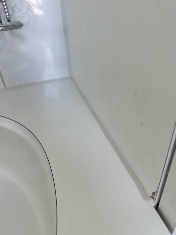 Dieselbe weisse Ablage mit einer Fuge entlang der Wand, unten rechts ist die braune Stelle an der Kante noch sichtbar