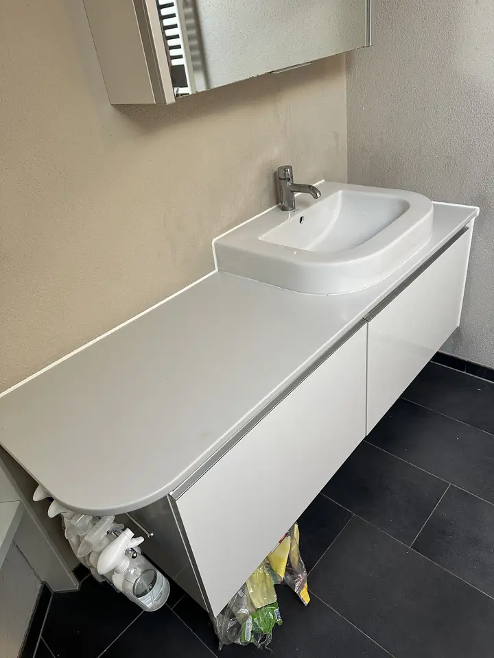 Derselbe weisse Waschtisch ohne Malerband, an der Wand ein schmaler heller Streifen