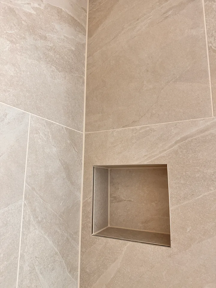 Quadratische Nische mit schmalem Metallrand in einer Wand aus grossen beigen Platten