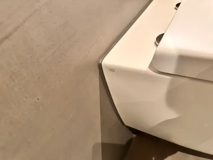 Weisses Hänge-WC von der Seite vor einer taupefarbenen Wand, Nahaufnahme