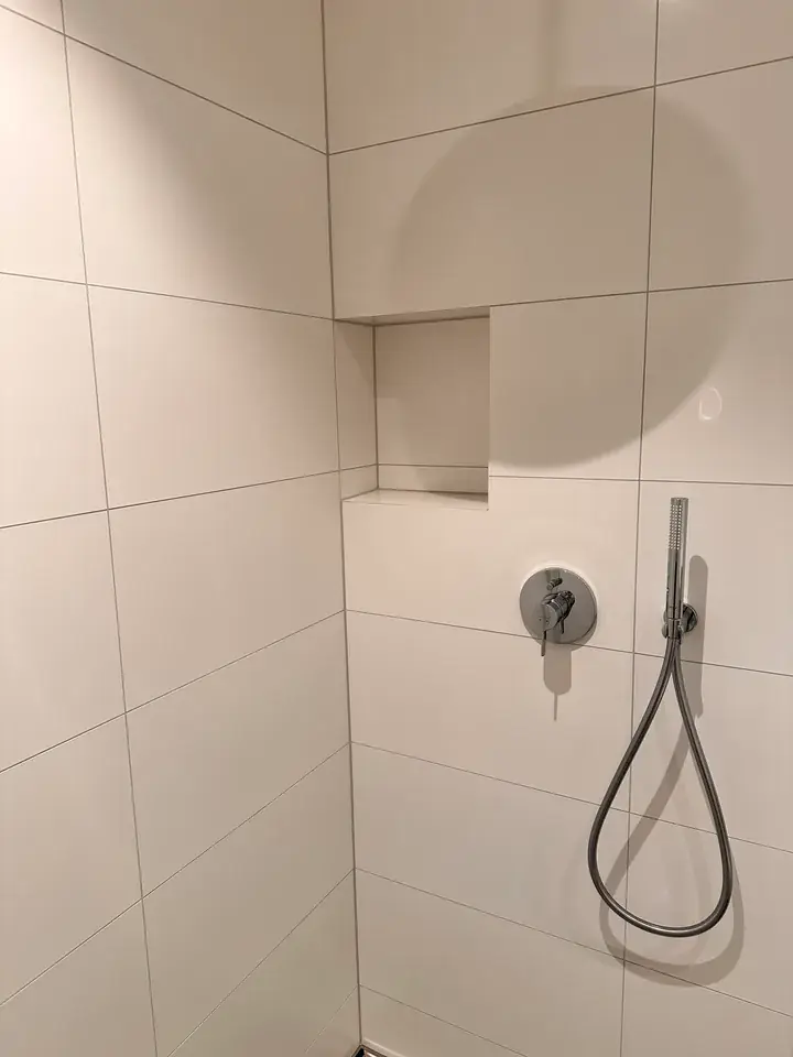Weisse geflieste Nische über der Duscharmatur