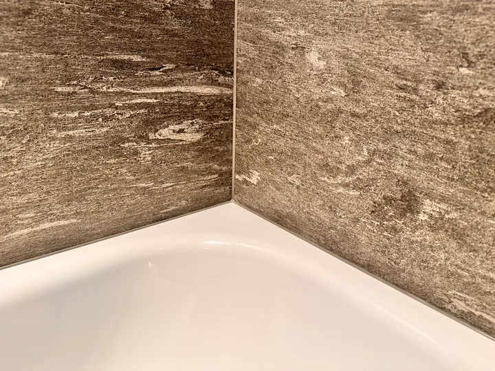 Wannenrand vor Wandplatten in brauner Steinoptik