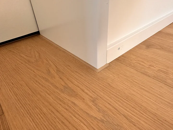 Parkettboden am Übergang zur weissen Sockelleiste