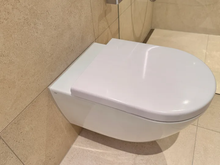 Weisses Hänge-WC vor beigen Wandplatten
