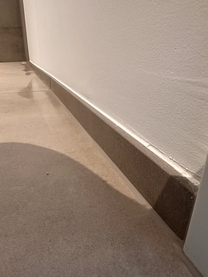 Bodenplatten am Übergang zur weissen Wand mit Sockelstreifen